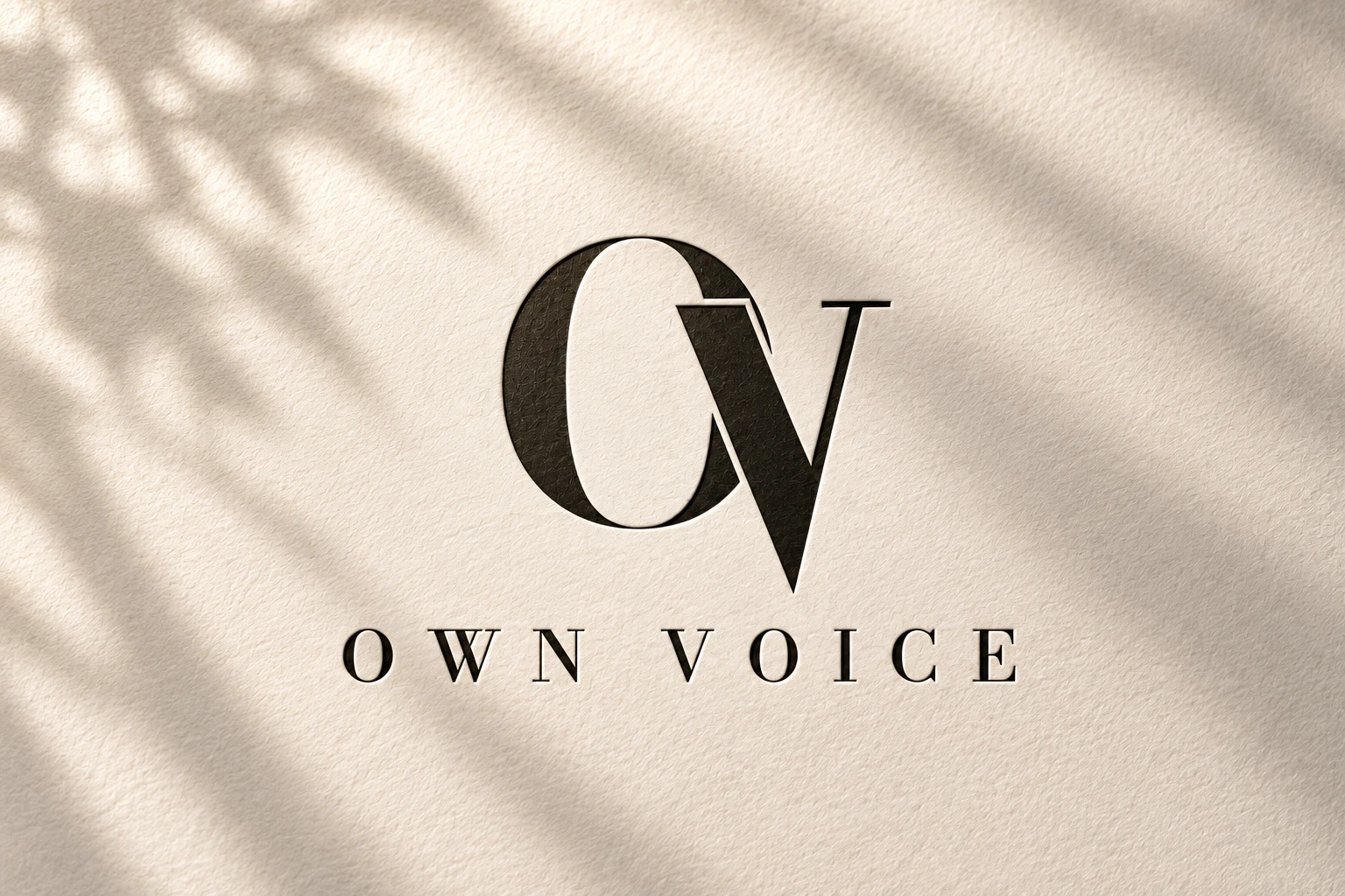 OWN Voice Logo, geprägt auf elfenbeinfarbenem Papier im Morgenlicht